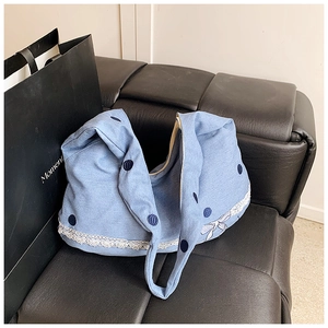 Détail du sac cabas en denim bleu avec dentelle blanche et broderies de pois bleu foncé
