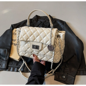Detail of white quilted crossbody bag with silver twist lock and chic metallic charm