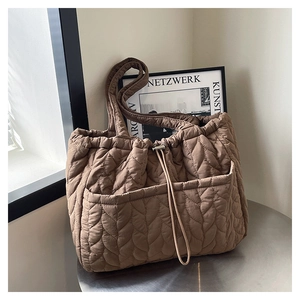 Close-up of brown quilted tote bag with leaf pattern stitching and metal drawstring buckle