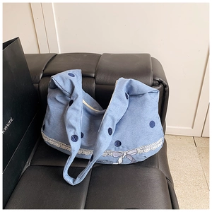 Détail du sac cabas en jean à pois bleus avec bordure en dentelle blanche et nœud