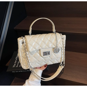 Detail of quilted leather handbag with metallic twist-lock and gold chain strap