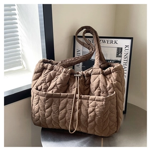 Detail of wave-quilted brown tote bag showing nylon texture and drawstring pocket