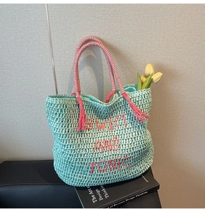Detail of mint green straw tote with pink SWIM AND TONIC embroidery and fringe tassel