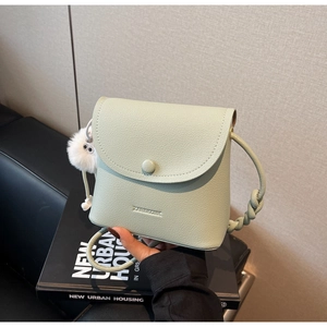 Detail of mint green lychee pattern leather crossbody bag with cute plush ball charm