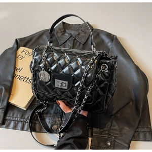 Detail of black quilted leather handbag featuring silver metal chain and lock buckle
