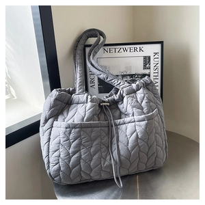 Detailed view of grey quilted tote bag with feather-pattern texture and side pockets