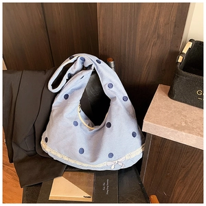Détail du sac cabas en toile à pois bleus avec bordure en dentelle et nœud délicat