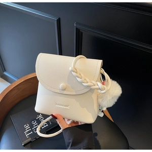 Detail of white litchi pattern leather bag with woven handle and plush charm accessory