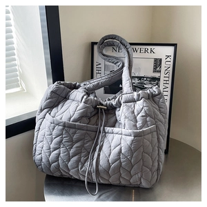 Detail of leaf-shaped quilting and drawstring closure on light gray tote bag