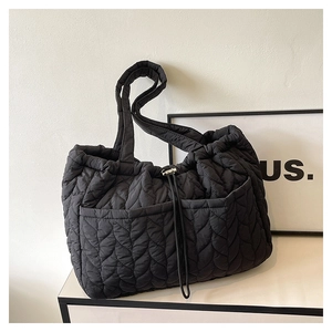 Detail of black quilted nylon tote bag showing wave stitching and drawstring closure