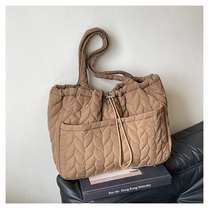 Quilted caramel tote bag with leaf pattern stitching and drawstring front pockets detail