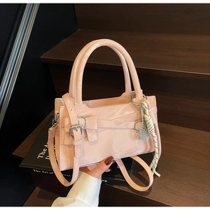 Dettaglio borsa a mano in pelle verniciata rosa con fiocco e ciondolo in corda intrecciata