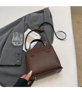 Details der dunkelbraunen Tasche mit Lychee-Leder, verstärktem Griff und Schultergurt