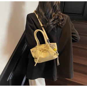Cremegelbe Plissee-Eimertasche mit Schleife, am Modell gezeigt für Größenperspektive