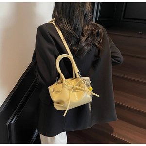 Detail der gelben Beuteltasche mit Schleife und Bommel-Anhänger am Modell