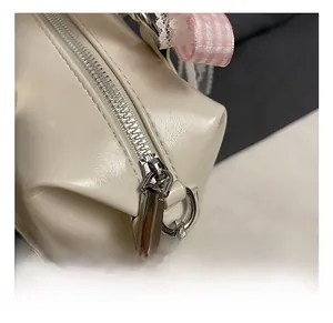 Detailed close-up of the smooth silver zipper and hardware on a cream leather handbag