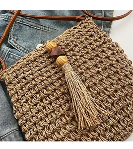 Dettaglio della borsa a tracolla in paglia con nappe decorative e perline in legno