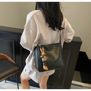Vue détaillée du sac seau en cuir noir avec un pendentif lapin en peluche accessoire