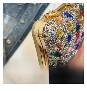 Detailed macro view of luxury clutch bag featuring multi-colored crystals and gold chain hooks