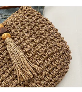 Dettaglio borsa di paglia bohémien con trama intrecciata, perline di legno e frange