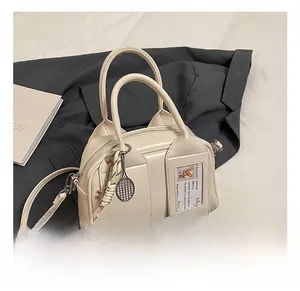 Detail view of cream Boston bag with decorative cartoon card slot and charm accents