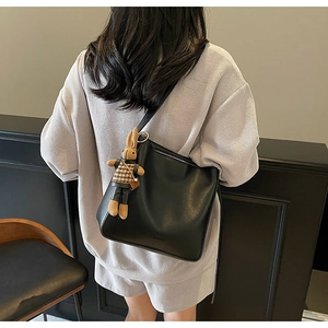 Détail du sac seau noir en cuir avec pendentif lapin en peluche et texture lisse