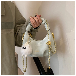 Detail of light green pleated handbag with golden chain strap and plush pendant charm
