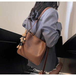 Sac fourre-tout en cuir marron avec breloque lapin porté par un mannequin
