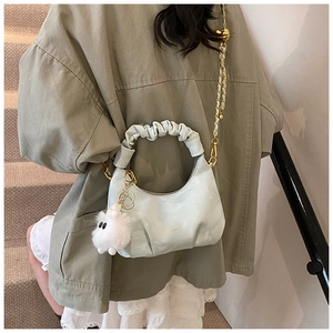 Détail du sac à plis bleu clair avec chaîne dorée et breloque en peluche douce