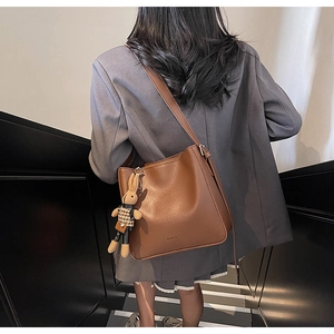 Sac seau en cuir marron porté à l'épaule avec breloque lapin et bandoulière réglable