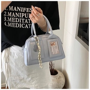 Detail view of light blue Boston bag with transparent card slot and tennis charm