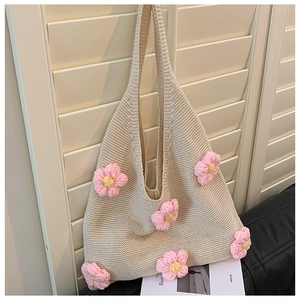 Close-up of cream knit tote bag featuring intricate handmade crochet pink flower details