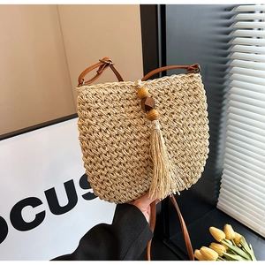Dettaglio della borsa a tracolla in paglia intrecciata a mano con cinturino in pelle e nappa