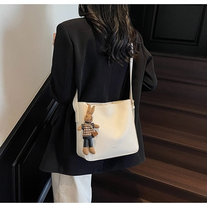Détail du grand sac cabas crème avec charm lapin mignon porté par un mannequin chic