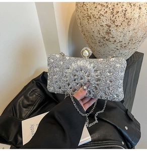 Détail d'une pochette de soirée luxueuse ornée de strass argentés et fermoir perle