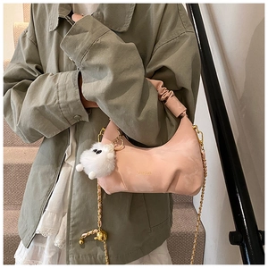 Détail d'un sac hobo plissé rose avec bandoulière chaîne dorée et logo frontal