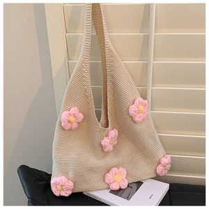 Close-up of beige knit tote bag with 3D pink and yellow floral accents and soft texture