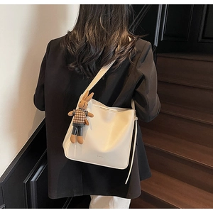 Détail du sac seau en cuir crème avec logo embossé et pendentif lapin mignon