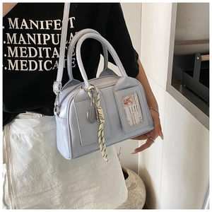 Detail of light blue Boston bag with glossy finish and tennis racket pendant accessory