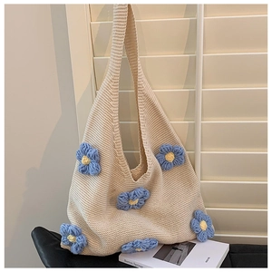 Detail of beige crochet tote bag with blue floral patterns hanging by a window
