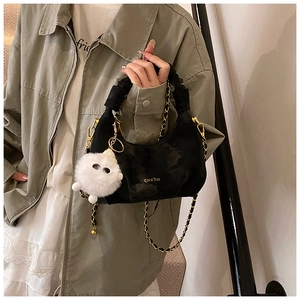 Black pleated dumpling bag with golden chain strap and plush monster charm detail