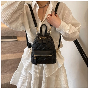 Detail eines schwarzen Mini-Rucksacks mit Steppmuster und goldenen Reißverschlüssen