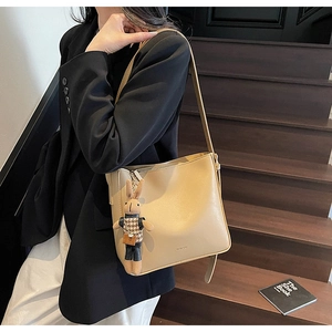 Sac seau bandoulière beige avec pendentif lapin, porté dans un look style urbain