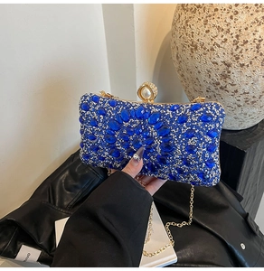 Gros plan détaillé des strass bleu royal et du fermoir perle sur une pochette de soirée