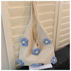 Detail of cream crochet tote bag with blue 3D flowers against a wooden shutter