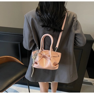 Rosafarbene glänzende Falten-Beuteltasche mit Schleife und Kette auf grauem Blazer-Rücken