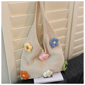 Detail of hand-knitted beige hobo bag showing 3D crochet flowers and rich texture
