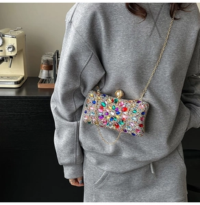Detail of colorful rhinestones on evening clutch with elegant pearl clasp and gold chain