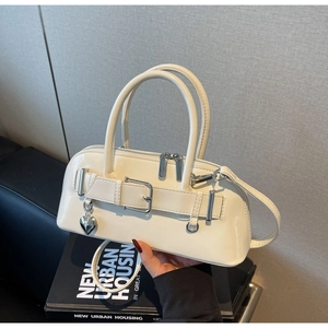 Détail du sac bowling crème avec finition brillante et charm coeur en métal argenté