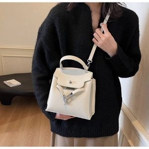 Detail einer cremeweißen Handtasche mit Lychee-Muster und silbernem Drehverschluss